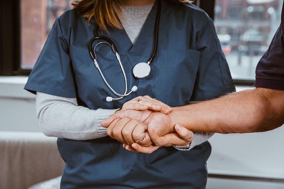 A nurse is holding a patient\'s wrist to check the pulse.